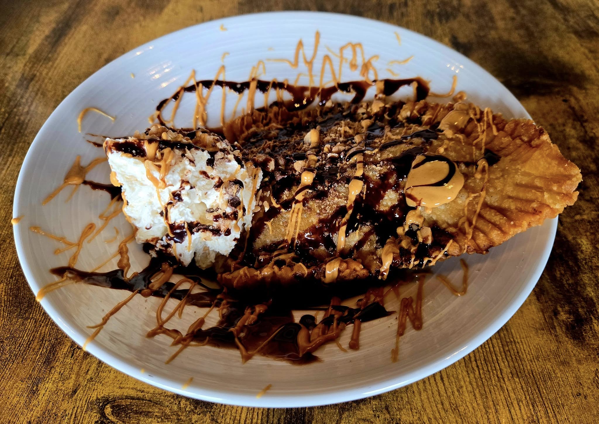 Fried dessert with whipped cream, chocolate, and peanut butter drizzle