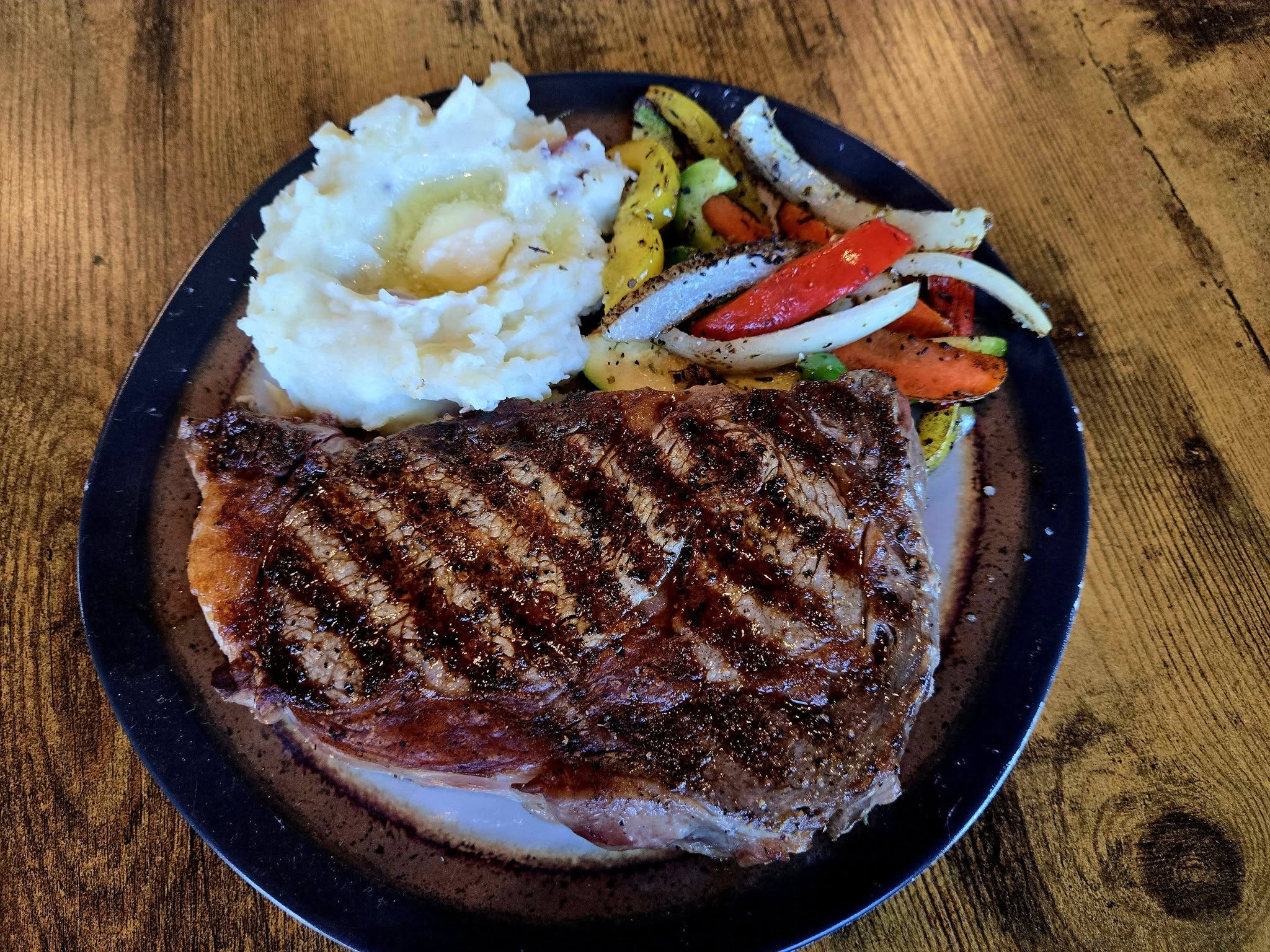 Grilled ribeye steak with mashed potatoes and roasted vegetables