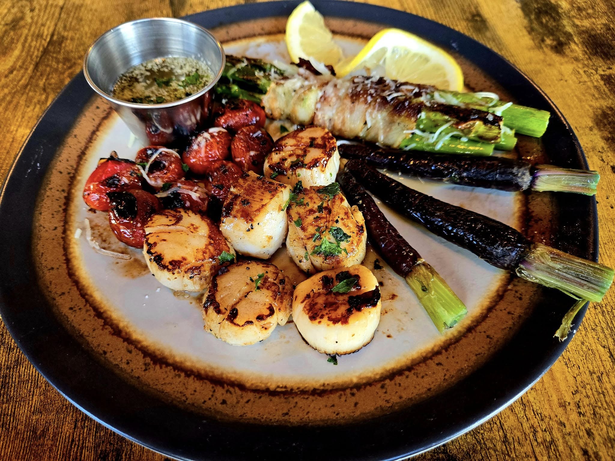 Seared scallops with roasted tomatoes, asparagus, and grilled lemon