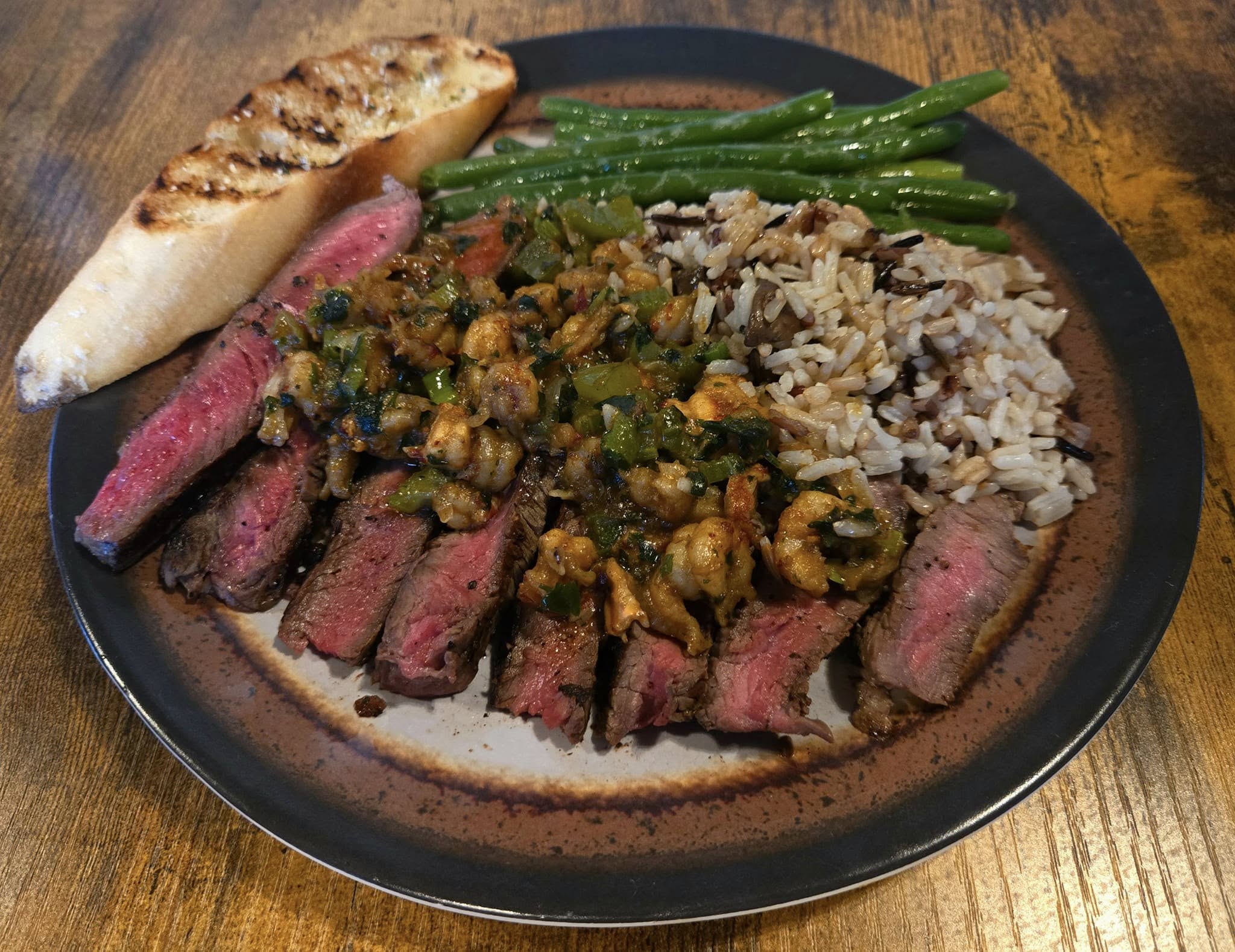 Sliced steak with garlic toast, wild rice, and green beans