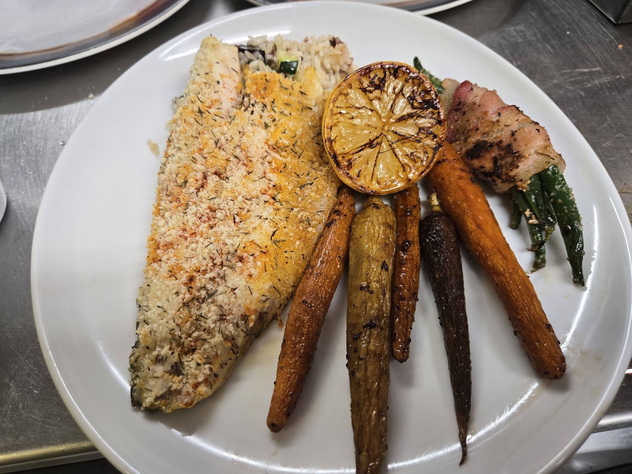 Baked trout with rice pilaf, roasted carrots, and grilled lemon